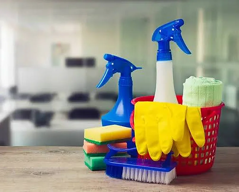 Städmaterial på ett bord: sprayflaskor, svampar, gula gummihandskar och en borste